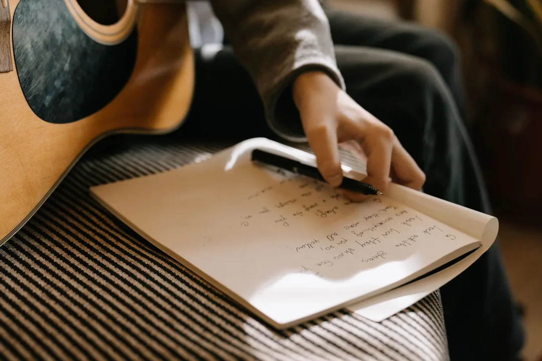 Compositor escribiendo una cancion con una guitarra